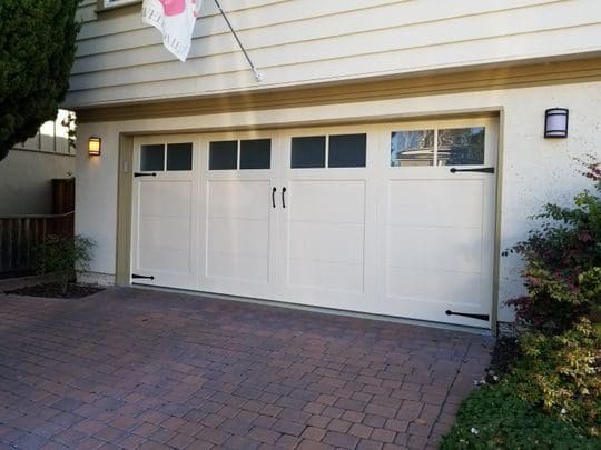 White garage door with brick driveway.