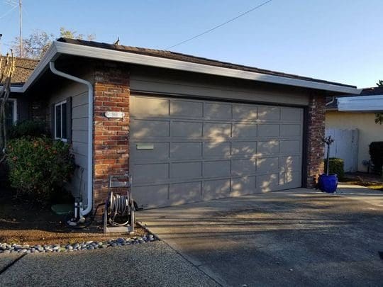 Garage door with brick exterior and landscaping.